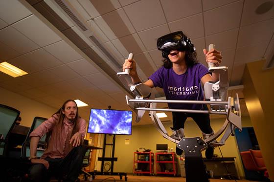 Photo of a Chatham University student in a virtual reality machine in the Immersive Media lab, 一位教授看着